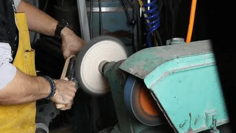 operator conditioning cloth buffing wheel using a rake tool to remove melted glue residue